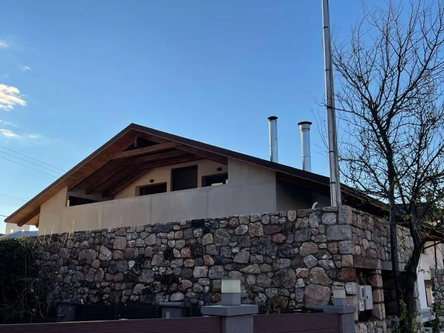 Το σαλέ με την ξύλινη στέγη πάνω από πέτρινο τοίχο